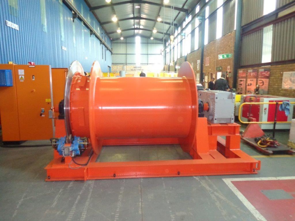 Winches SA custom single-drum electric shaft winder with a large grooved steel wire-rope drum on a heavy skid frame, of the type manufactured in Silverton, Pretoria for the Gautrain shaft-sinking programme