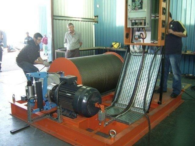 Winches SA technicians factory-testing a custom electric shaft winder with a grooved steel wire-rope drum, motor drive and control panel, of the type manufactured in Silverton, Pretoria for the Ingula Pumped Storage Scheme